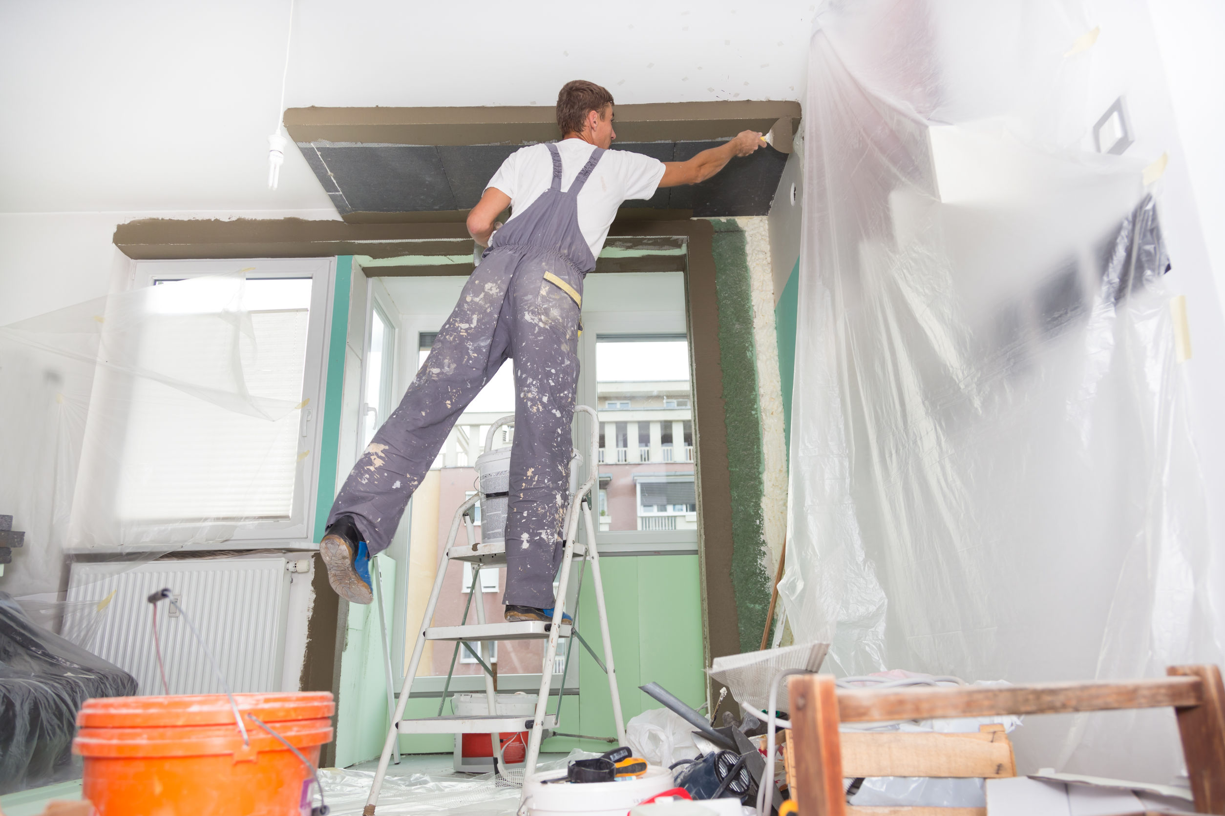 artisan professionnel, Artisan plaquiste posant une couche de plâtre sur les murs et le plafond d'un appartement
