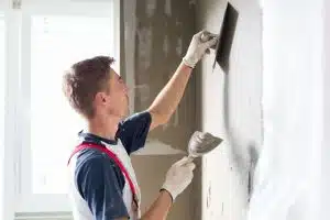 métier plaquiste, homme appliquant du plâtre sur le mur d'un logement en rénovation ou en construction, trouver meilleur plâtrier plaquiste