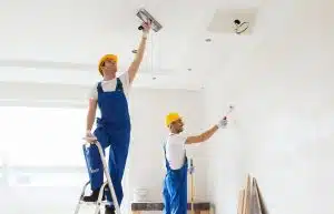 platrier plaquiste, Ouvrier terminant la finitions des murs et du plafond avec une couche de plâtre