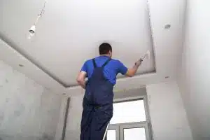 homme installant un faux-plafond suspendu dans une chambre